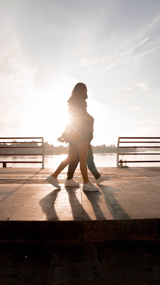 Photo by Angga Pratama a couple of people that are walking on a sidewalk