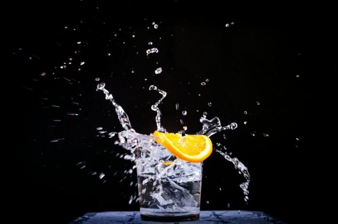 splash of water in drinking glass with sliced lemon