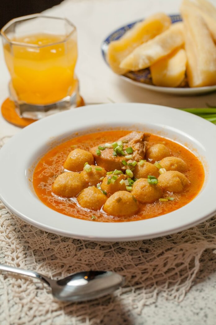 Photo by Maggi Paraguay A bowl of soup on a table with a glass of orange juice