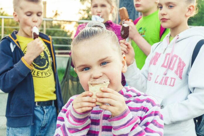 Photo by Vitolda Klein boy in white and pink striped long sleeve shirt holding ice cream