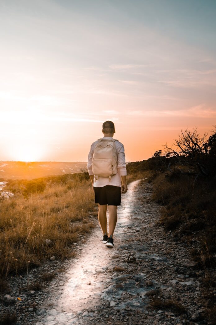 Photo by Adam Thomas man in white dress shirt and brown shorts walking on dirt road during daytime