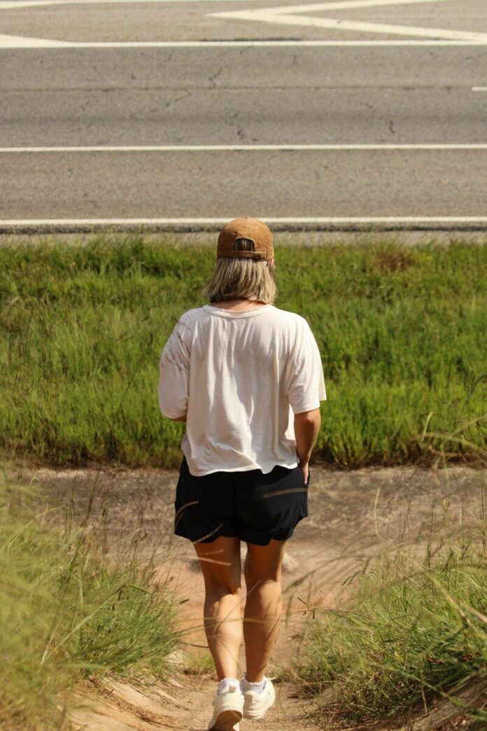 Photo by Mark Stuckey A woman walking down a dirt path next to a road